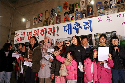 지난 2월 이뤄진 주민-정부 간 이주 합의에 따라 이달 말까지 이 마을을 떠나야 하는 경기도 평택 대추리와 도두리 주민들이 24일 대추리 농협창고에서 마지막이 될 935번째 촛불문화제에 참석해 촛불을 밝히고 있다. 이날 문화제에 참석한 지킴이들이 무대에 올라 노래공연을 펼치고 있다. 
 